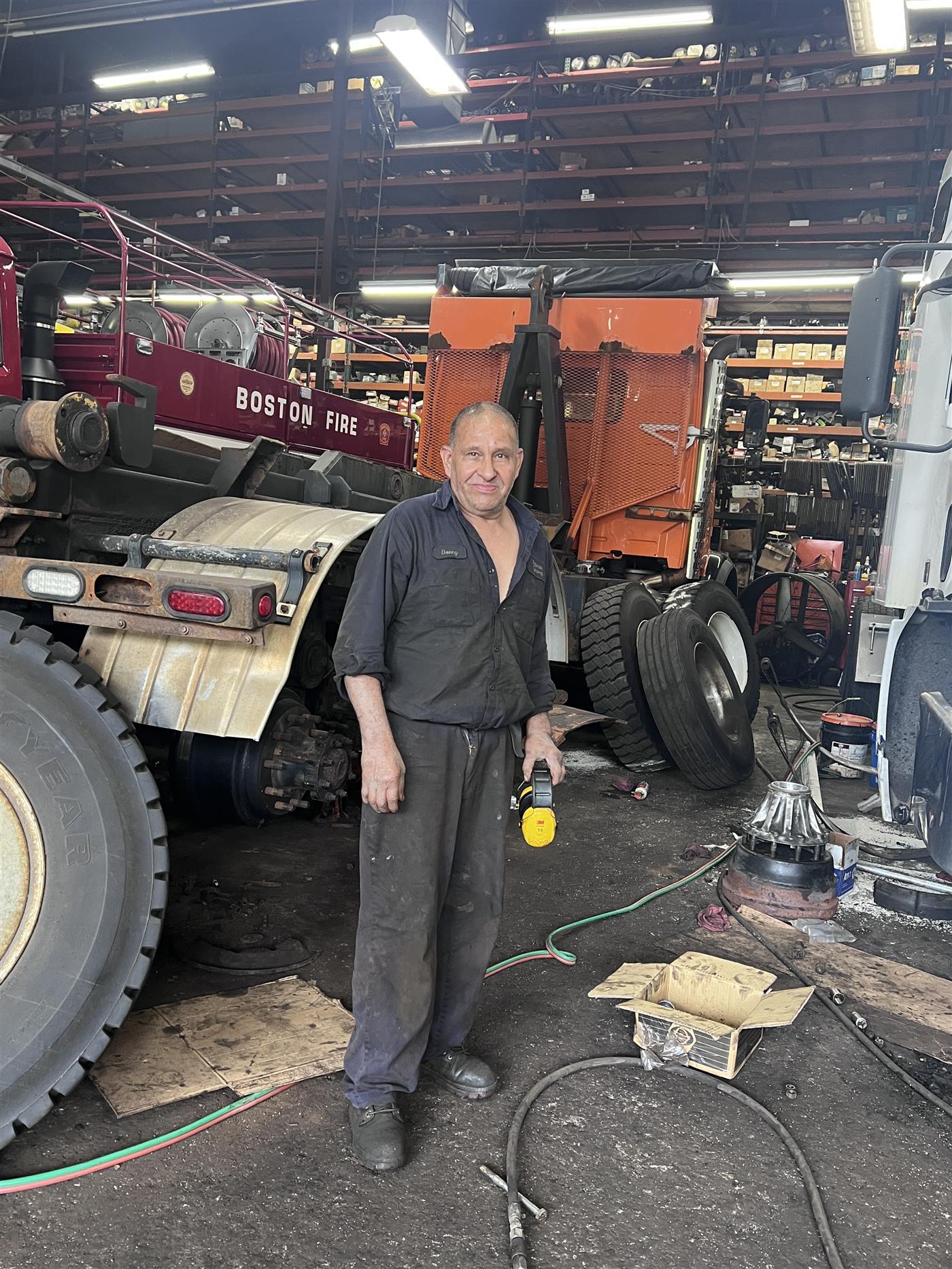A Palmer Spring Company technician standing beside a Boston Fire Department truck under repair in the Woburn shop