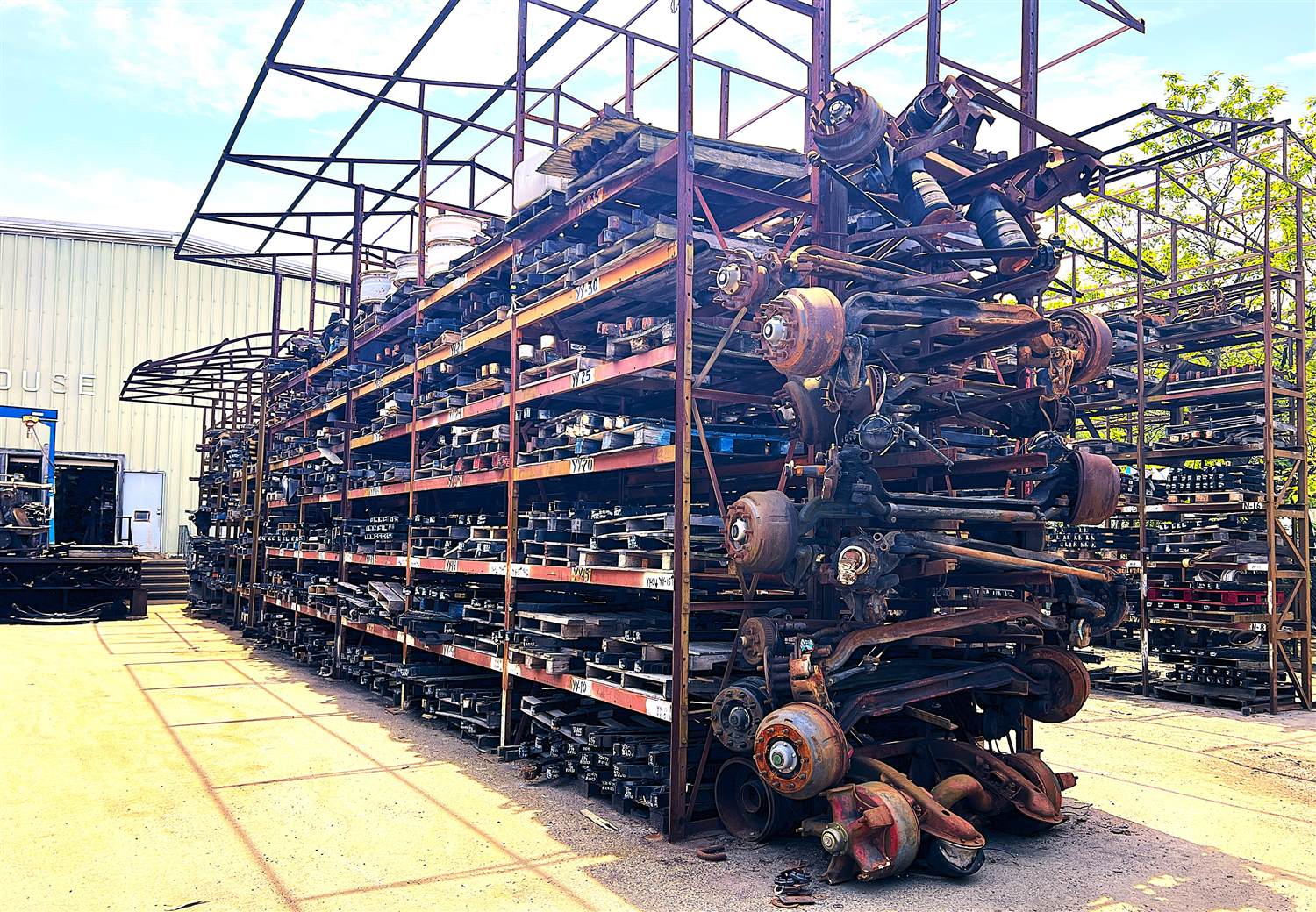 Rows of heavy-duty truck axles and suspension components on outdoor storage racks